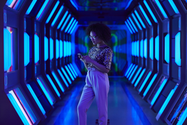 Young businesswoman looking at smartphone in spaceship like corridor