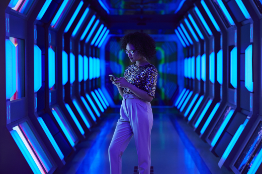 Young businesswoman looking at smartphone in spaceship like corridor