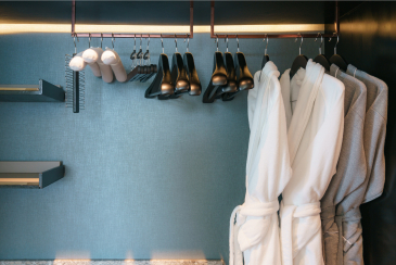 Four of gray and white bathrobe with wooden hangers in wardrobe in bathroom at luxury hotel.
