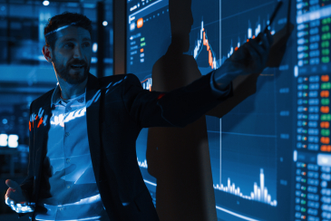 Business Conference Meeting Presentation: Businessman does Financial Analysis talks to Group of Businessspeople. Projector Screen Shows Stock Market Data, Investment Strategy, Revenue Growth